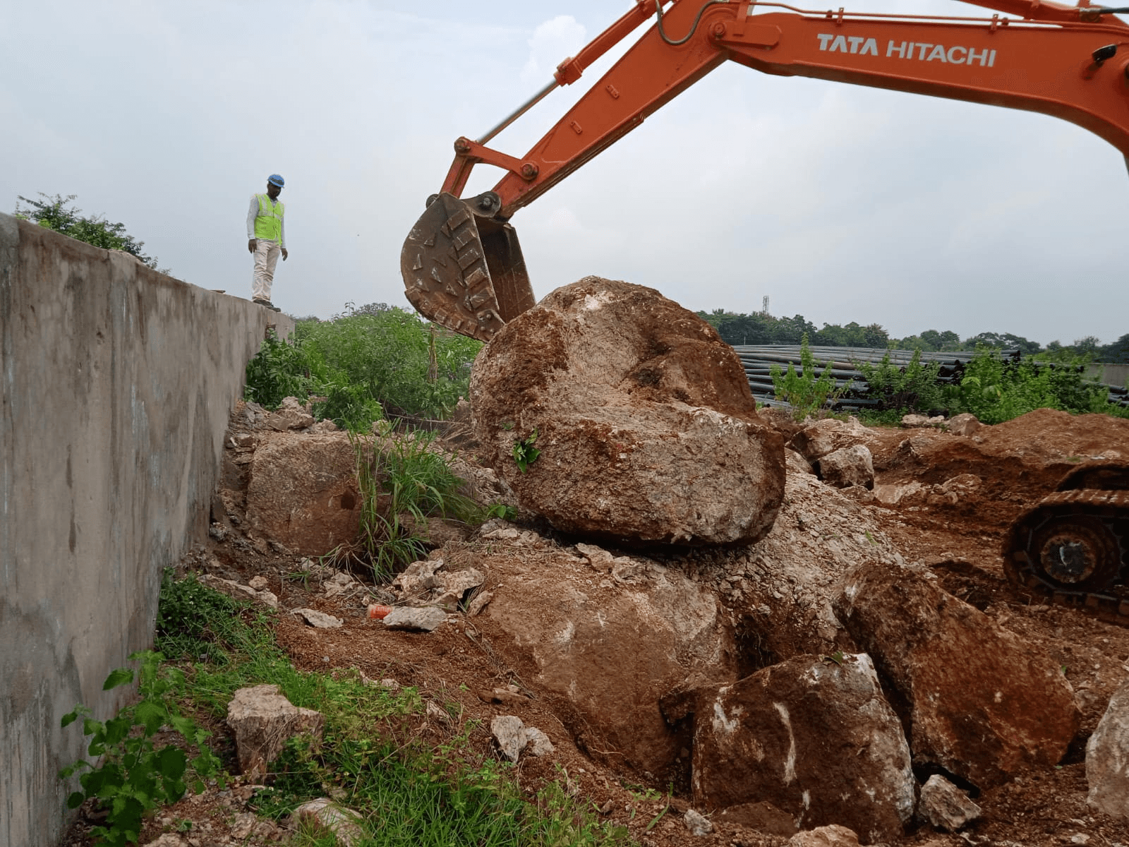 Excavator carrying out large boulder removal